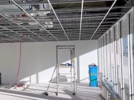 An office fit out with the suspended ceiling grid hung below the building services and the perimeter walls already lined.