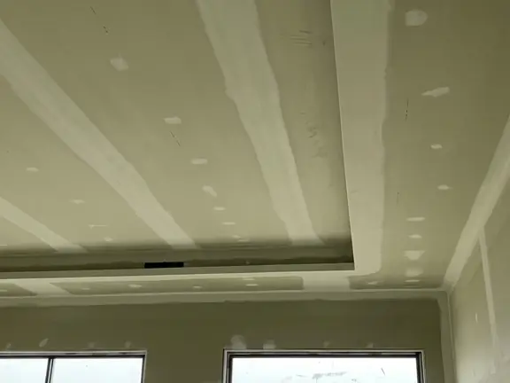 A raked ceiling sheeted and set above a window wall, the joints run out to the angle on each side.
